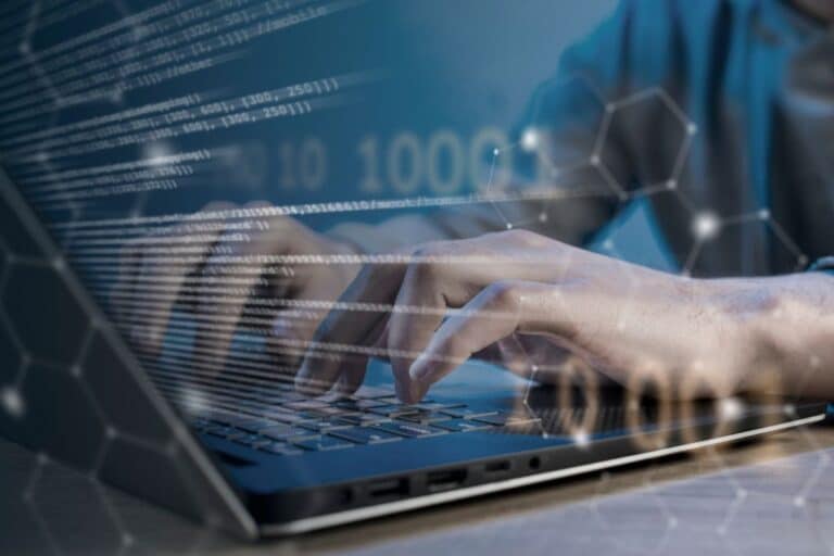 Manos escribiendo código en portátil con efectos visuales de datos, representando lenguaje de marcas y sistemas de gestión de la información.